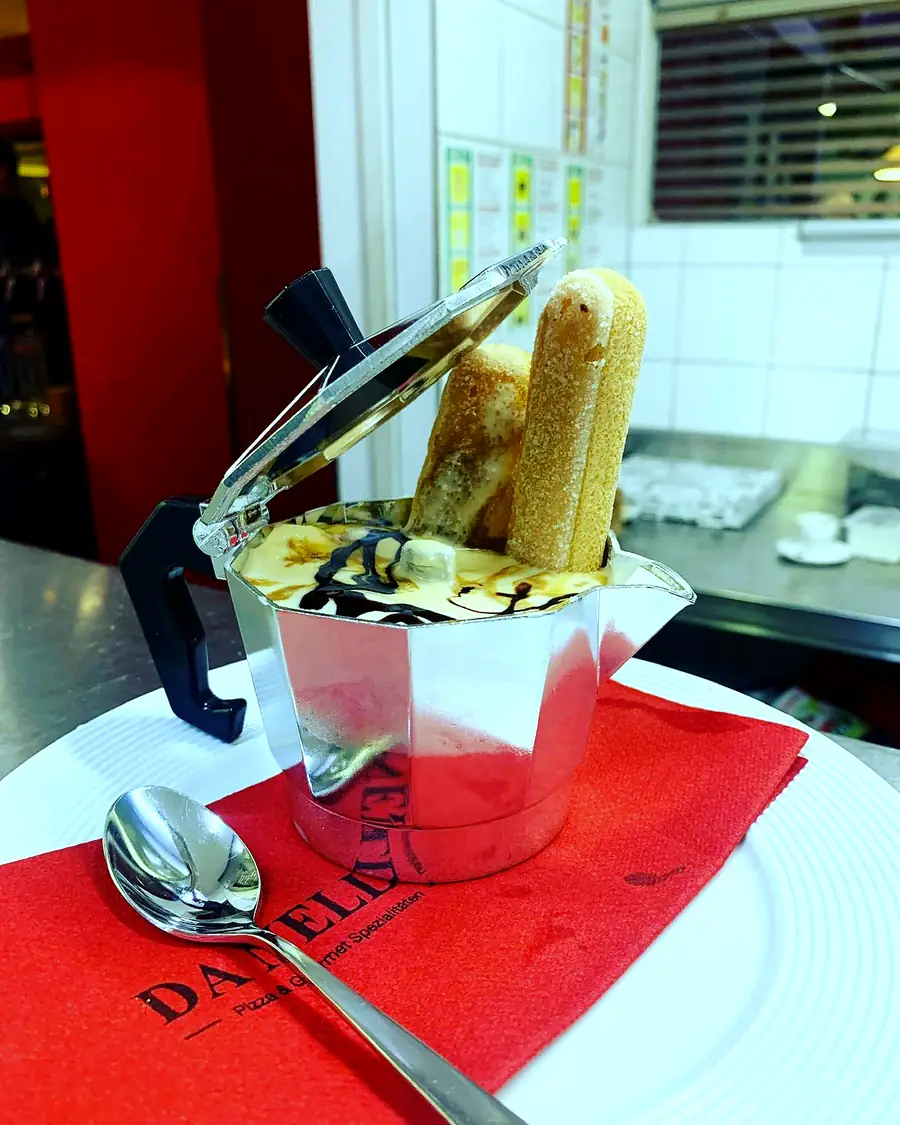 Kaffee in einer kleinen Moka-Kanne mit Biscotti auf roter Serviette