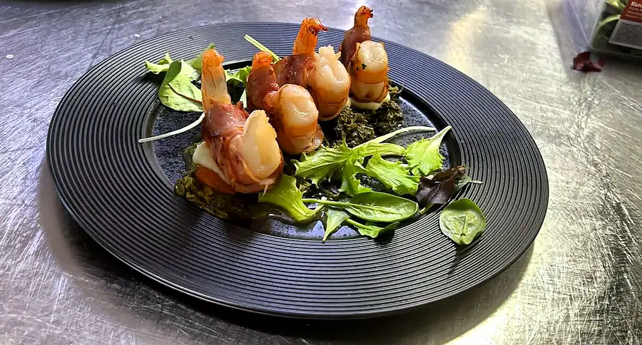 Garnelen auf Blattsalat auf schwarzem Teller