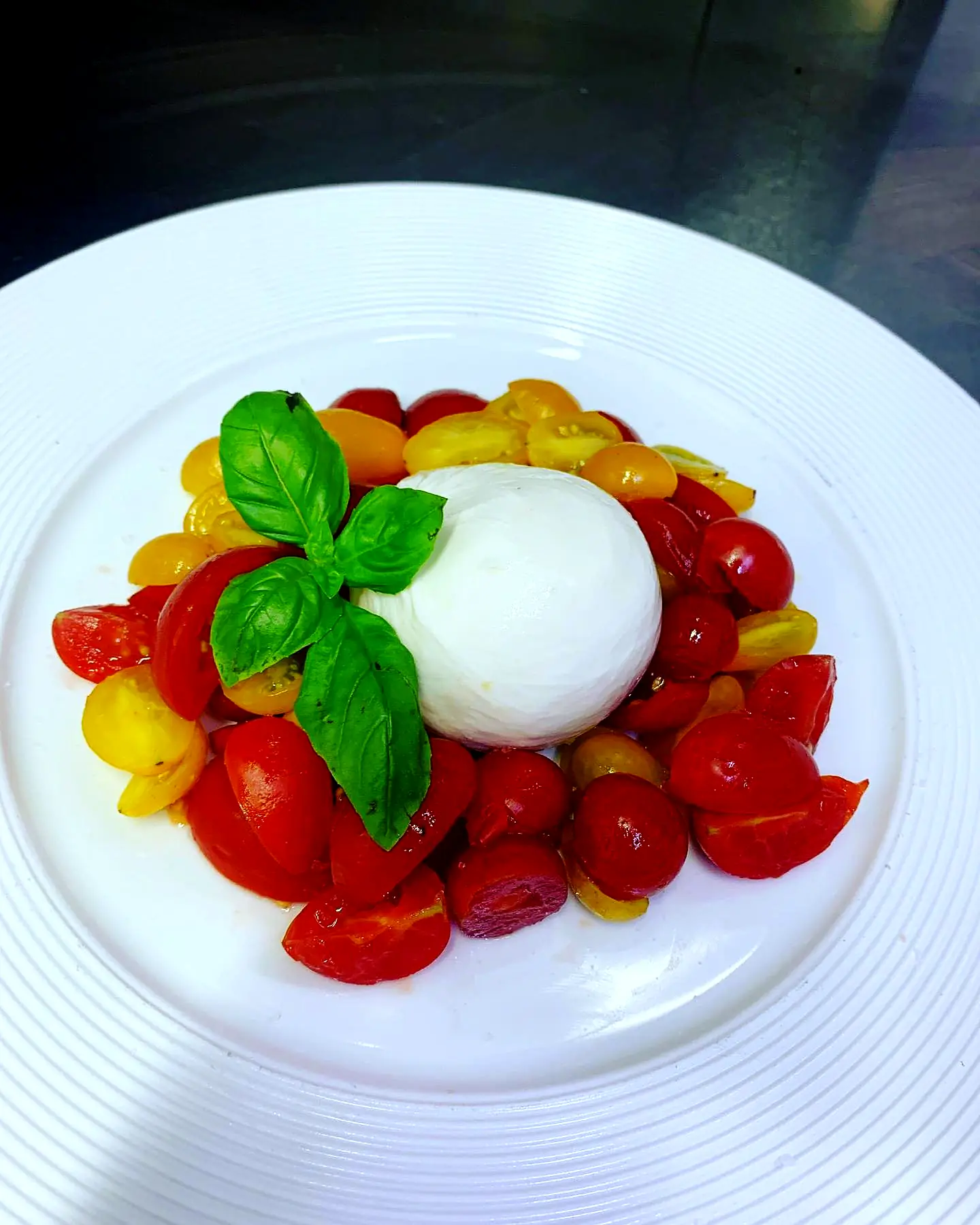 Burrata mit bunten Kirschparadeisern und Basilikum
