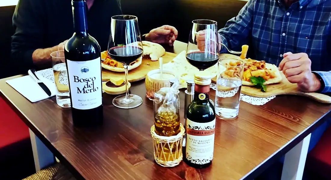 Gedeckter Tisch mit Rotwein, Weingläsern, Pasta und Balsamico